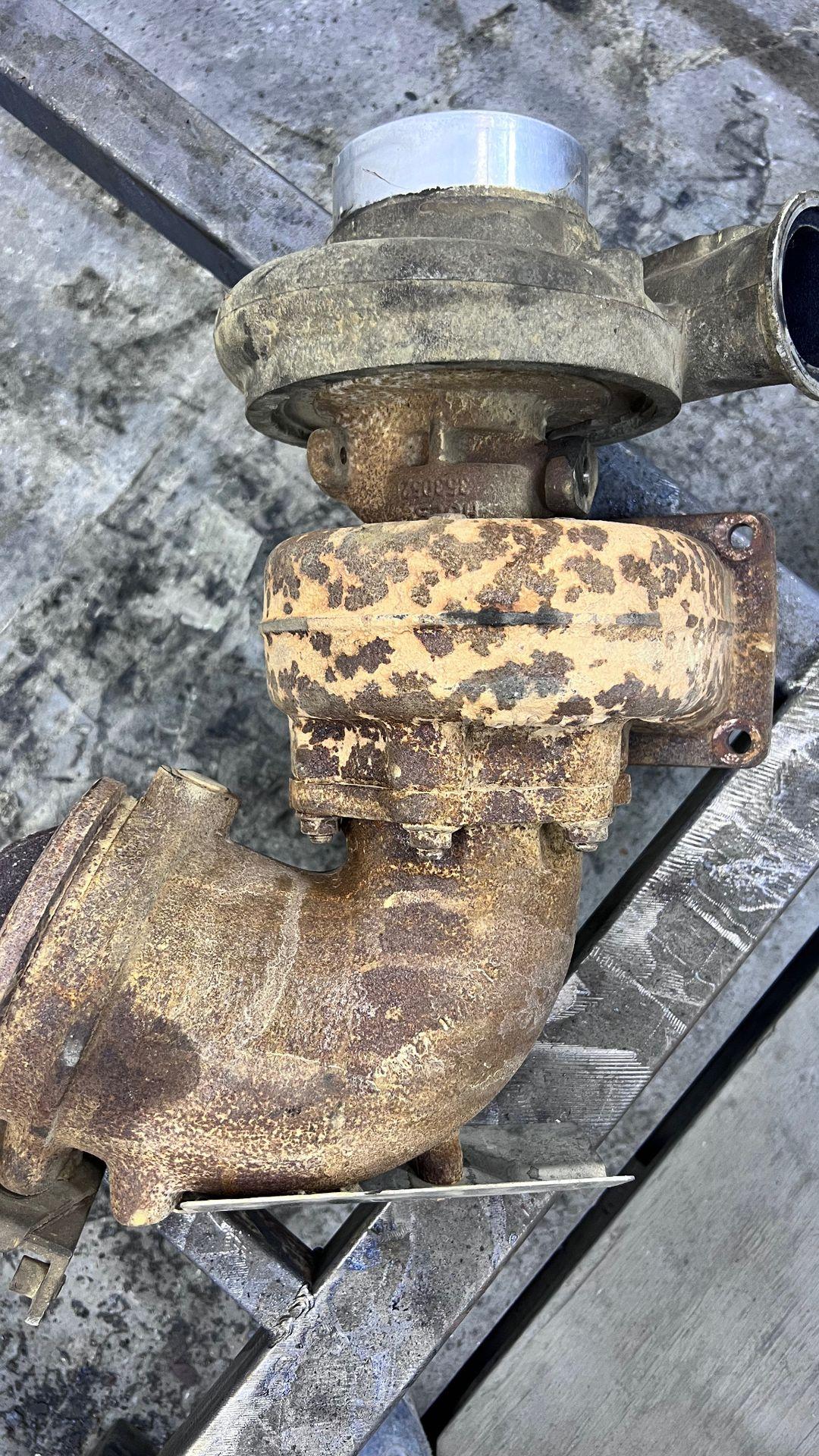 Rusty and weathered mechanical component with flanges and cylindrical parts on a metal surface.