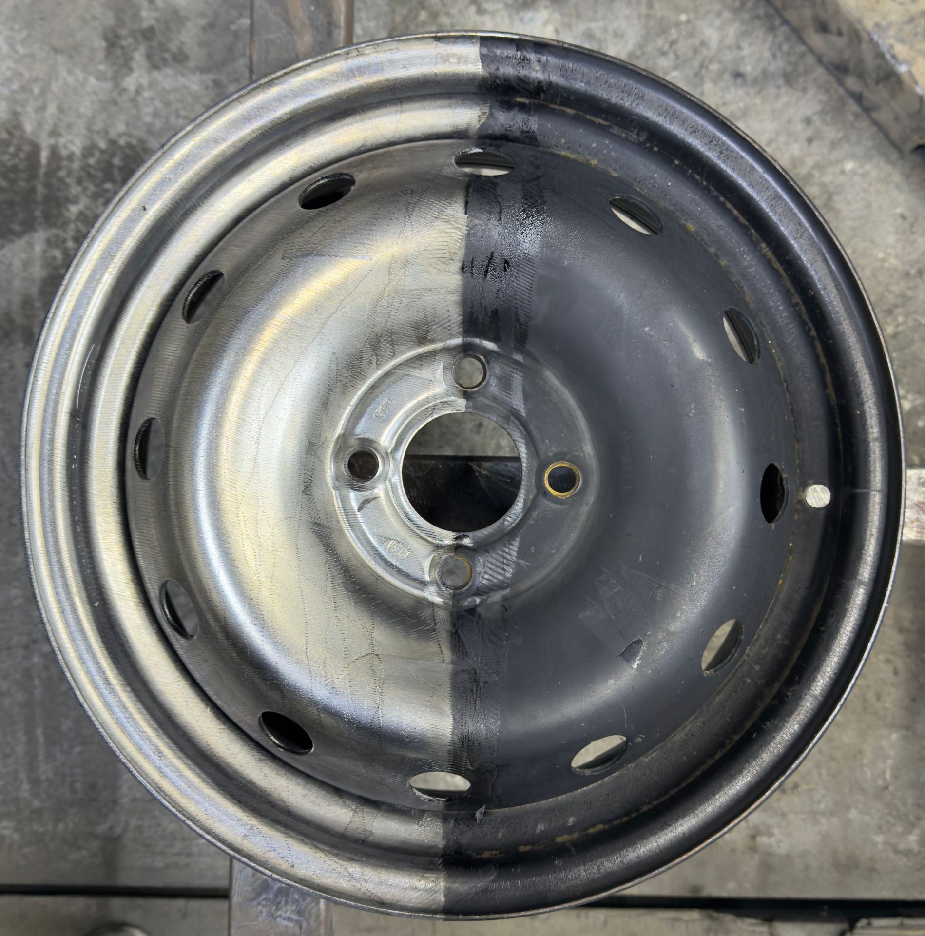 Steel wheel rim with half cleaned, showing a stark contrast between shiny and dirty surfaces.